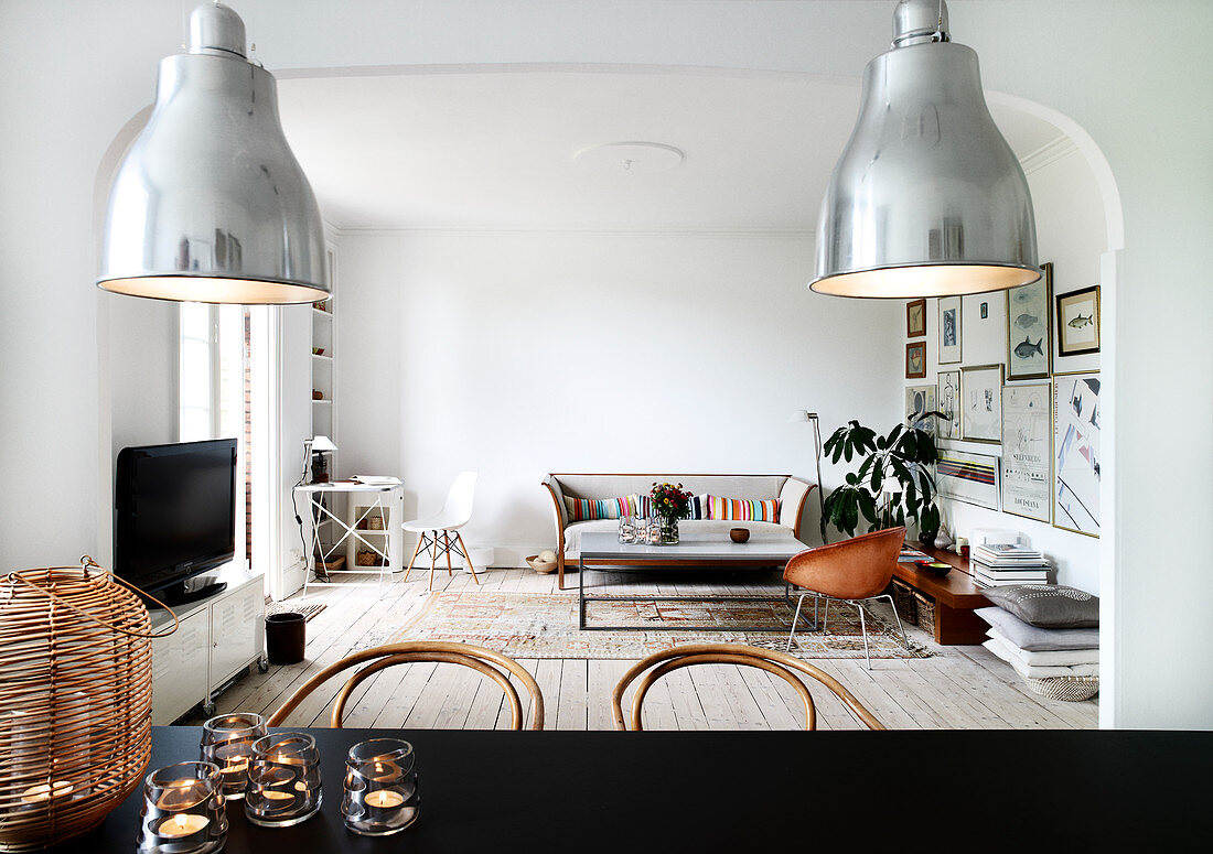 Blick über schwarzem Esstisch ins Wohnzimmer mit Schalenstuhl, Couchtisch und Couch