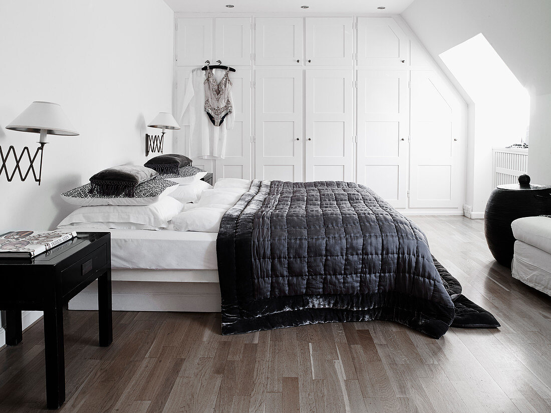 Queen bed with black quilt and white built-in wardrobe in the bedroom