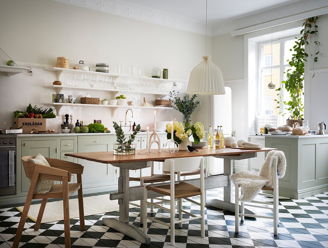 Tisch mit verschiedenen Stühlen in klassischer Küche mit Schachbrettboden