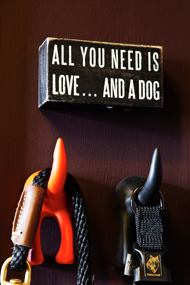 Funny wall hooks in the shape of a dog's tail with a message above
