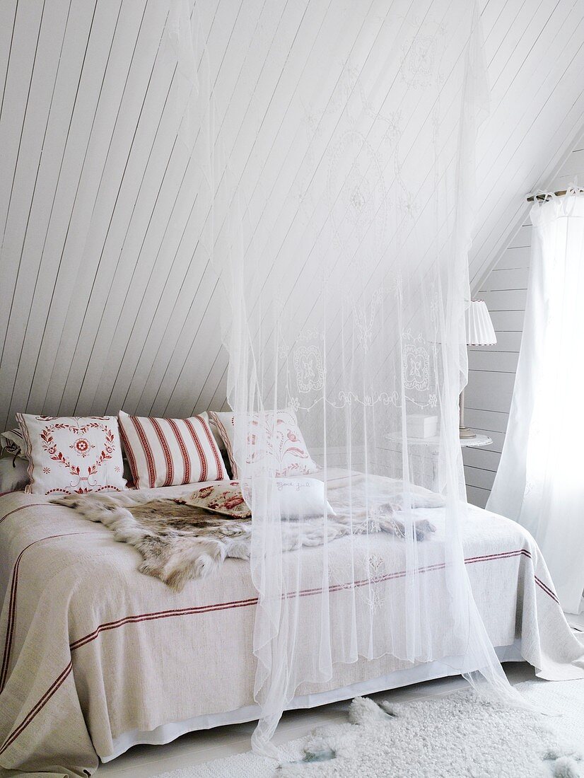 Tuch hängt vor dem Bett unter der Dachschräge mit Wandverkleidung