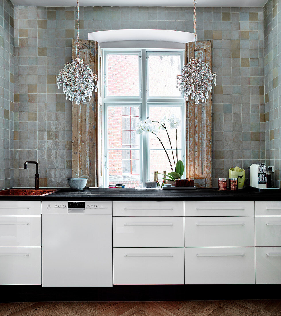White kitchenette with black worktop, above and chandelier
