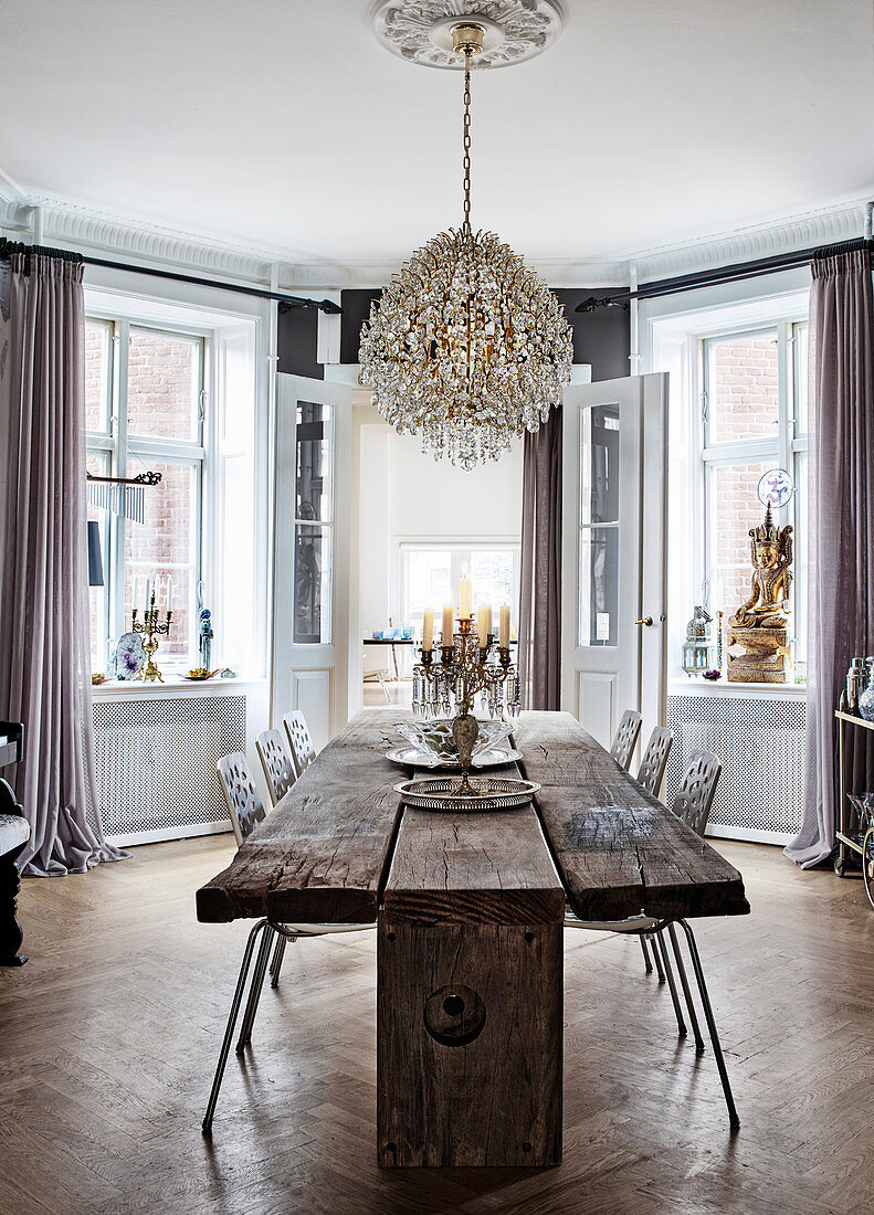 Rustic wooden table with modern chairs, above a chandelier in the dining room