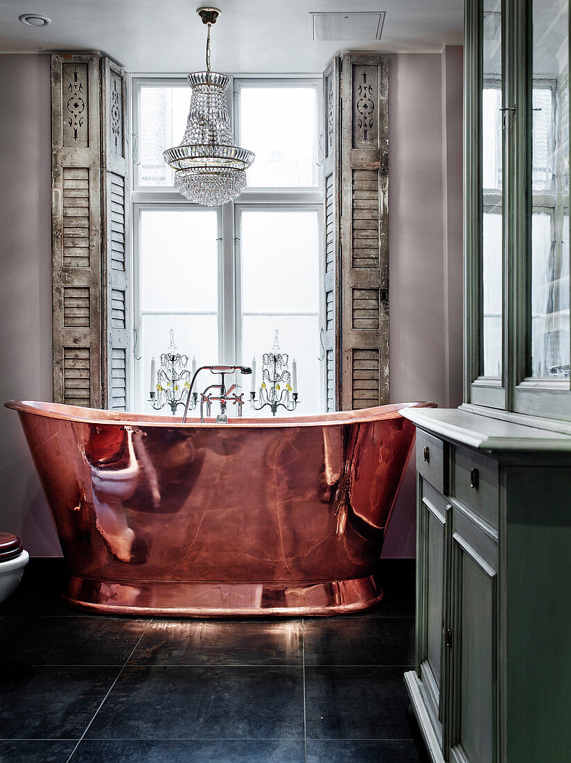 Copper bathtub in front of a window