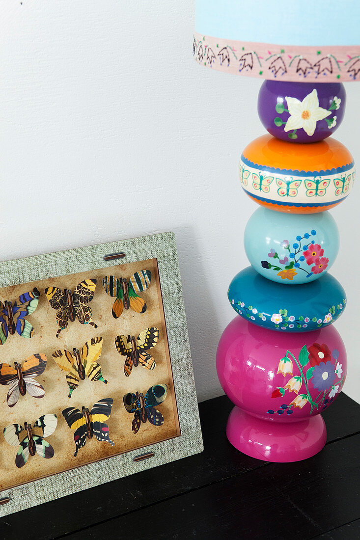 Table lamp with a decorative lamp base next to a showcase with butterflies