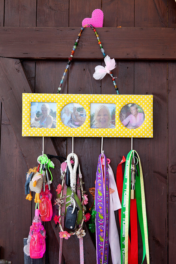 Familienfotos in gelb-weißem Passepartout, darunter Schlüsselanhänger an Holztür