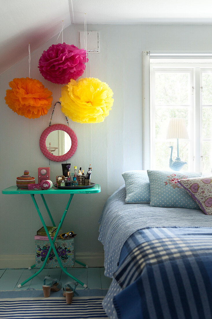 Colourful tulle flowers above a bedside table next to a bed in a bedroom