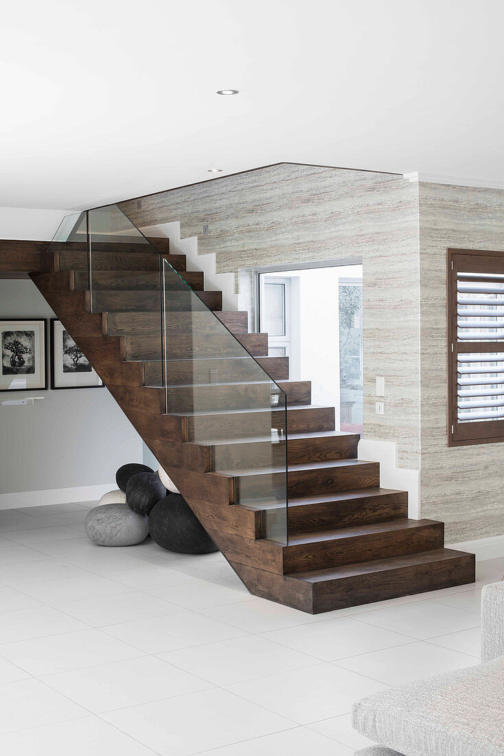 Dark wooden staircase with glass balustrade in modern interior