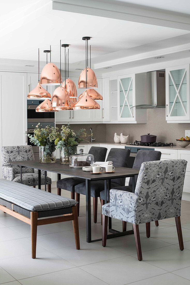 Copper ceiling lamps above dining table in kitchen-dining room
