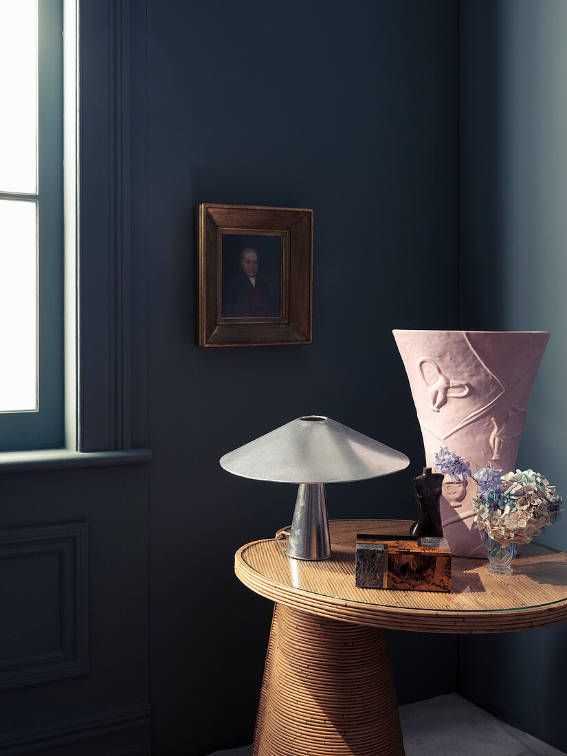 Beistelltisch mit Tischlampe und Vase in Zimmerecke, Portrait an der Wand