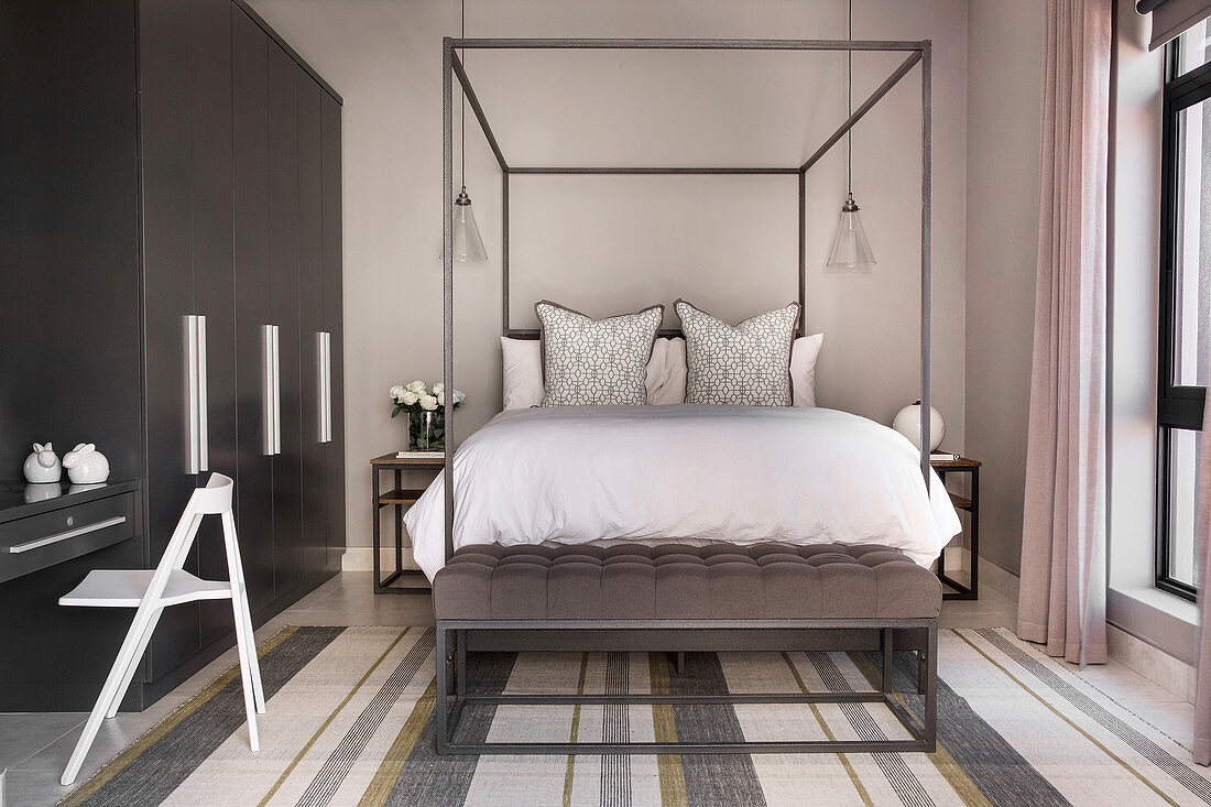 Modern four-poster bed in bedroom in shades of grey