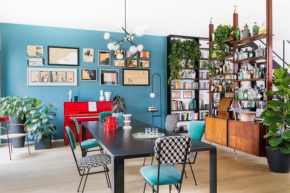 Dining table in front of blue wall in open-plan, vintage-style interior