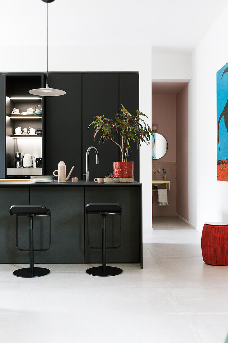 Barstools at island counter in open-plan kitchen with black fronts