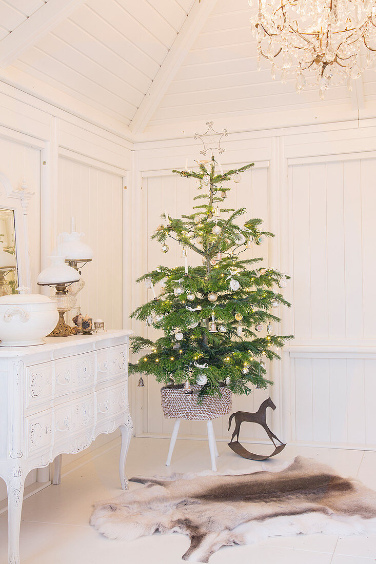 Christmas tree on stool next to white cabinet