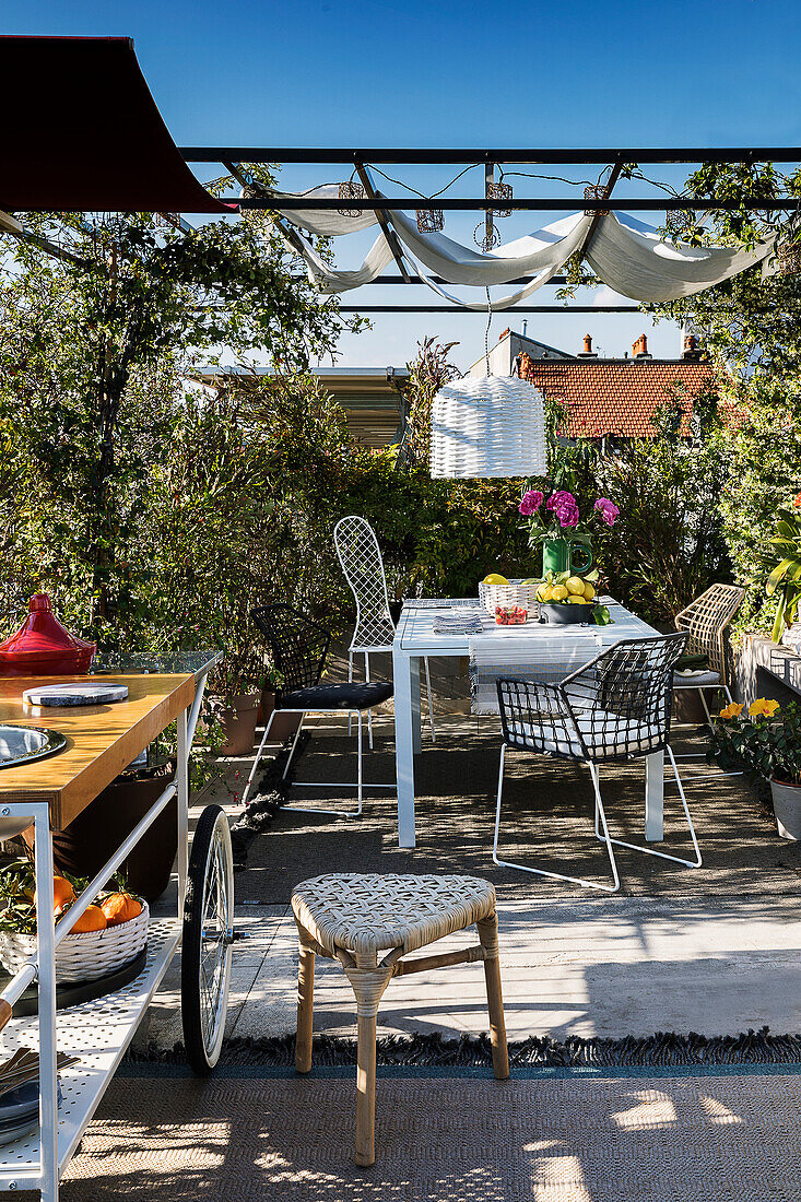 Dining table on roof terrace with pergola in summer