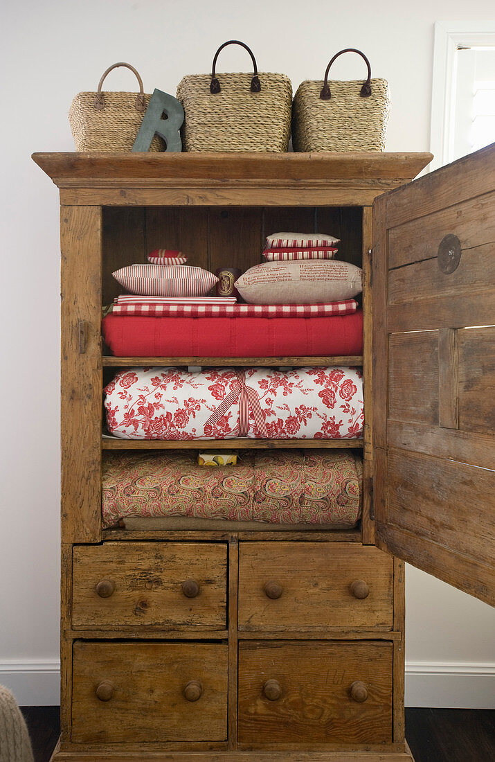 Red household textiles in old wooden cabinet with open door
