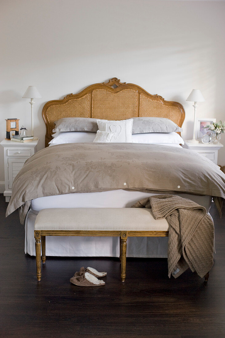 Polsterbank vorm antiken Bett im Schlafzimmer in Braun und Weiß
