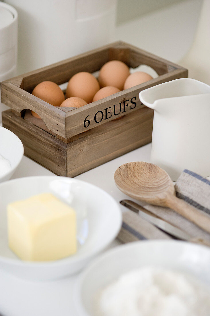 Eggs in small wooden box, baking ingredients and utensils