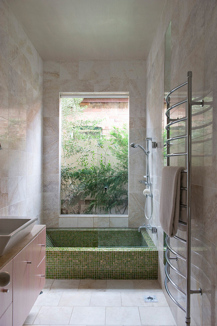 Mosaic bathrub below window in Mediterranean bathroom