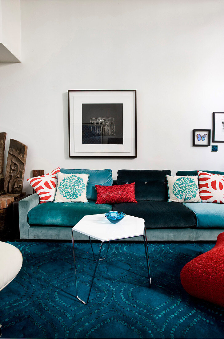 Gemütliches Polstersofa mit Kissen und filigraner Coffeetable auf blauem Teppich im Wohnzimmer