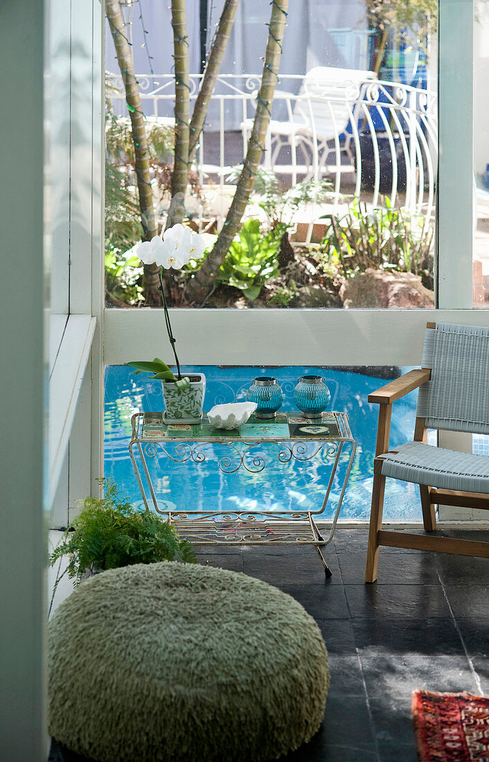 Blick vom Wohnzimmer mit schwarz lackiertem Fliesenboden auf Terrasse mit Wasserbecken