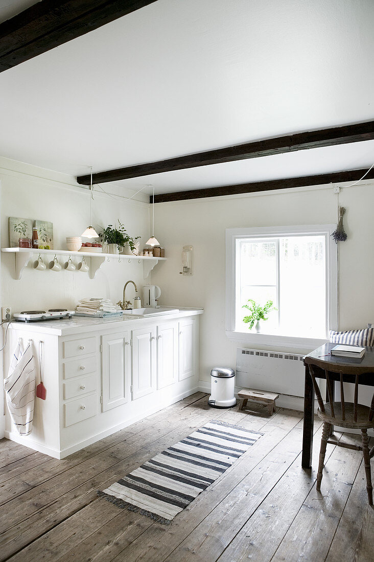 White kitchen counter in rustic kitchen-dining room with wooden floor