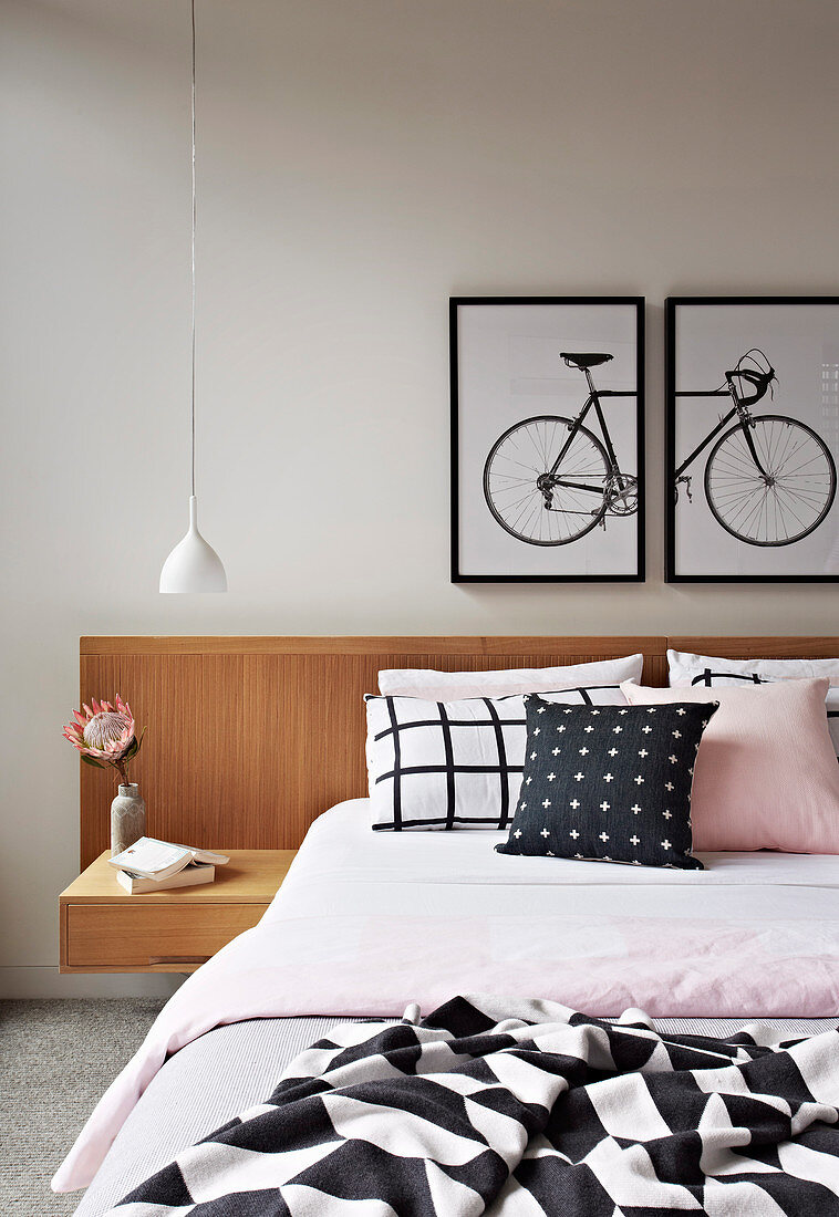 Doppelbett mit Betthaupt und integriertem Nachttisch, darüber zweiteiliges Bild mit Fahrradmotiv