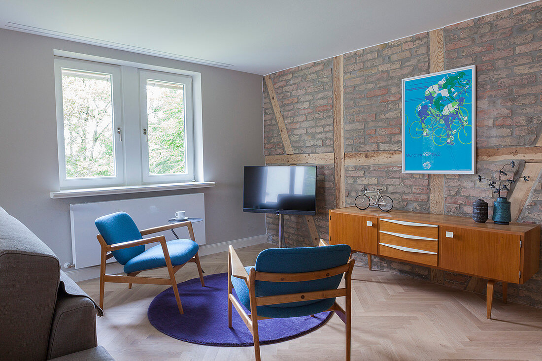 Fernseher, Sideboard und zwei Stühle im Wohnzimmer mit Ziegelwand
