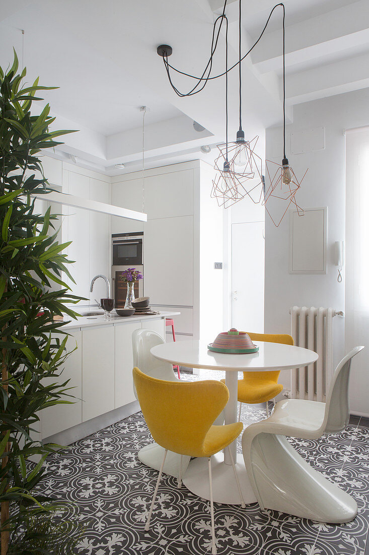 Runder Tisch mit gelben und weißen Klassikerstühlen vor Küchentheke
