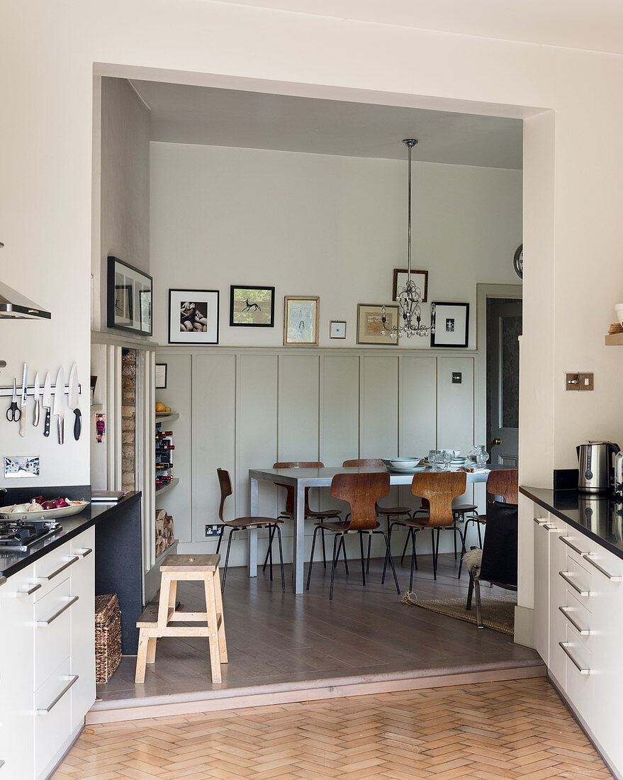 Blick aus L-förmigem Anbau mit Küche auf Wohnraum mit Esstisch vor Wandvertäfelung