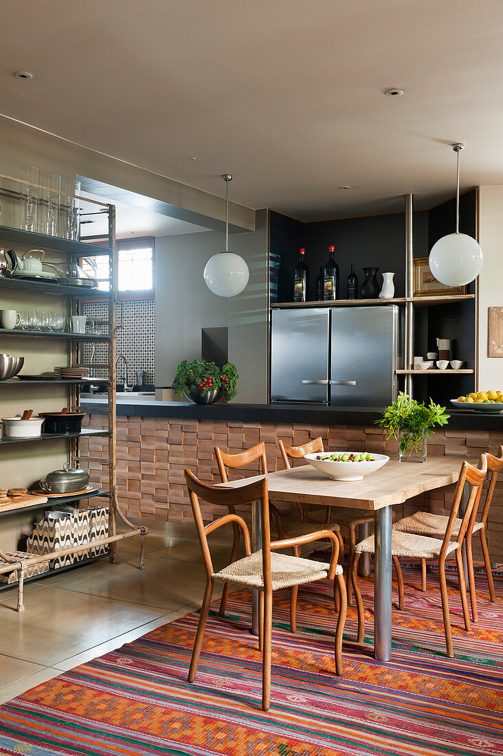 Wooden table and chairs on multicoloured rug in open-plan kitchen