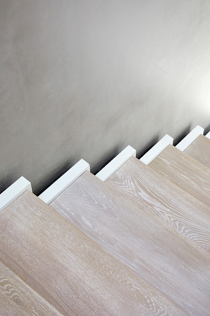 Detail einer modernen Holztreppe an grauer Wand