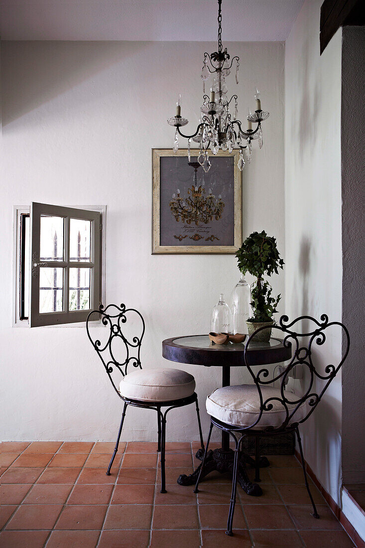 Kleiner runder Tisch mit nostalgischen Metallstühlen in Zimmerecke eines Landhauses