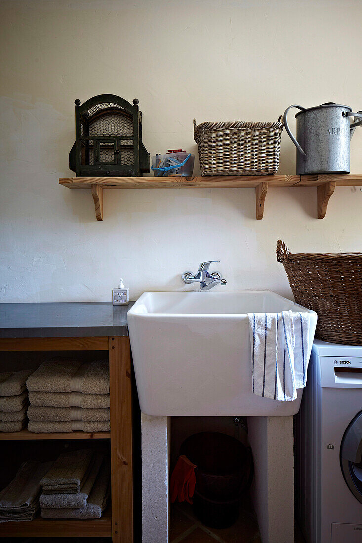 Kleiner Waschtisch zwischen Waschmaschine und Wäscheregal in Landhaus