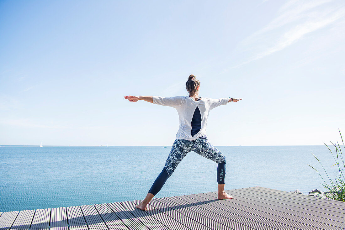 Frau macht Yoga-Übung am Meer