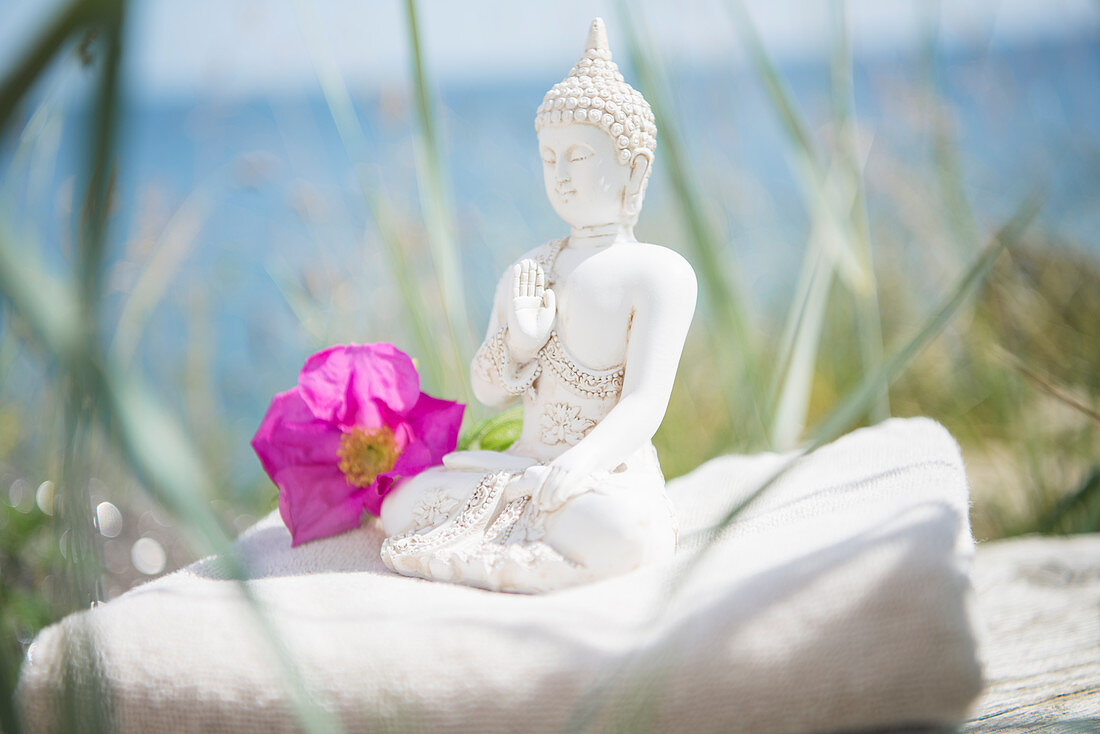 Buddhafigur mit Blüte auf Handtuch