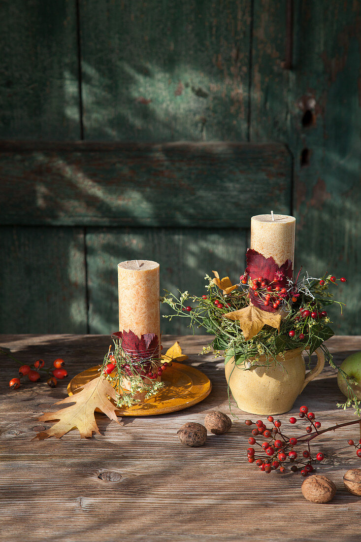 Herbstlich dekorierte Kerzen auf Teller und im Krug