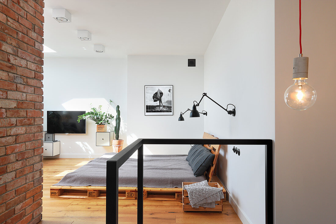 Palettenbett in Wohnraum mit Sichtmauerwerk und Loftcharakter