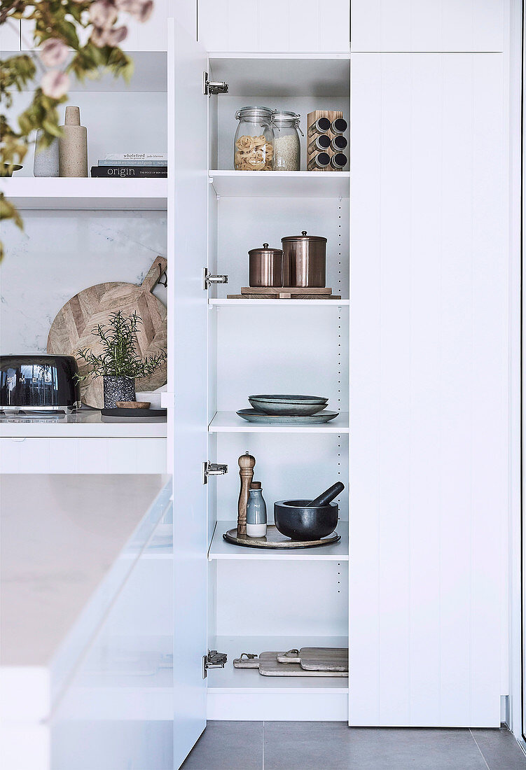 Geöffneter Küchenschrank in moderner weißer Küche