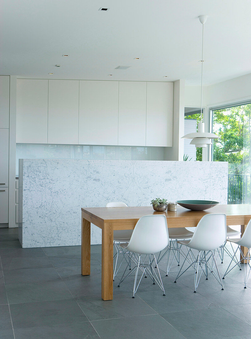 Dining table in front of the marble wall to the open kitchen