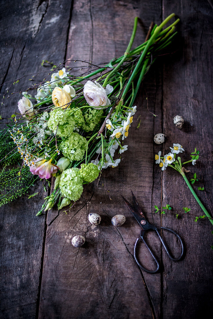 Tying an Easter bouquet of viburnum, freesias and ranunculus