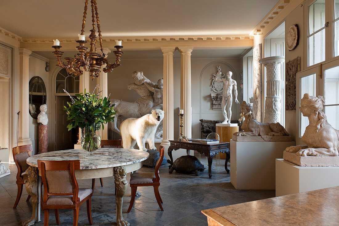 Entrance hall filled with a taxidermy polar bear, regency chairs, marble topped table and large plaster casts
