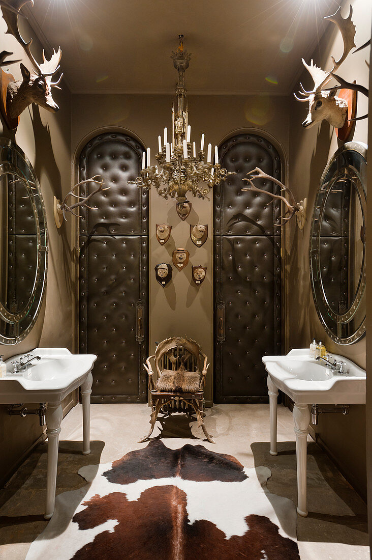 Cloakroom with french porcelain hand basins, padded leather doors, antlers and cow hide rug