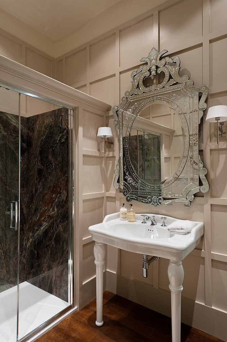 French porcelain handbasin below ornate mirror in panelled bathroom