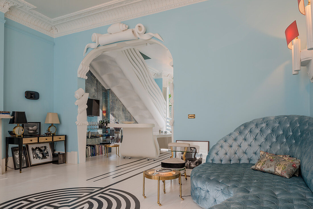 Sofa in sky-blue interior with arched doorway decorated with stucco elements