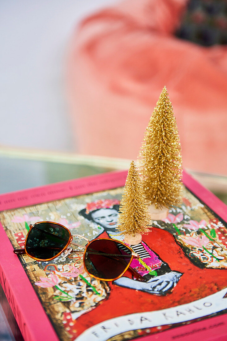 Sunglasses and golden mini fir trees on art book