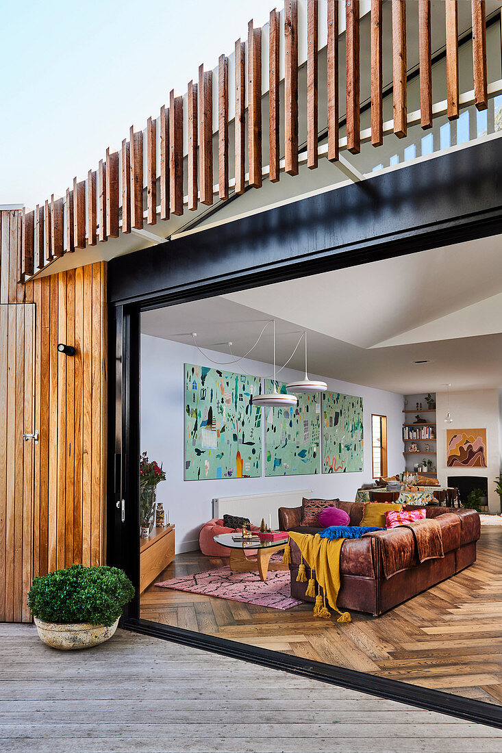 Blick durch breite Terrassen-Schiebetür in farbenfrohes Wohnzimmer