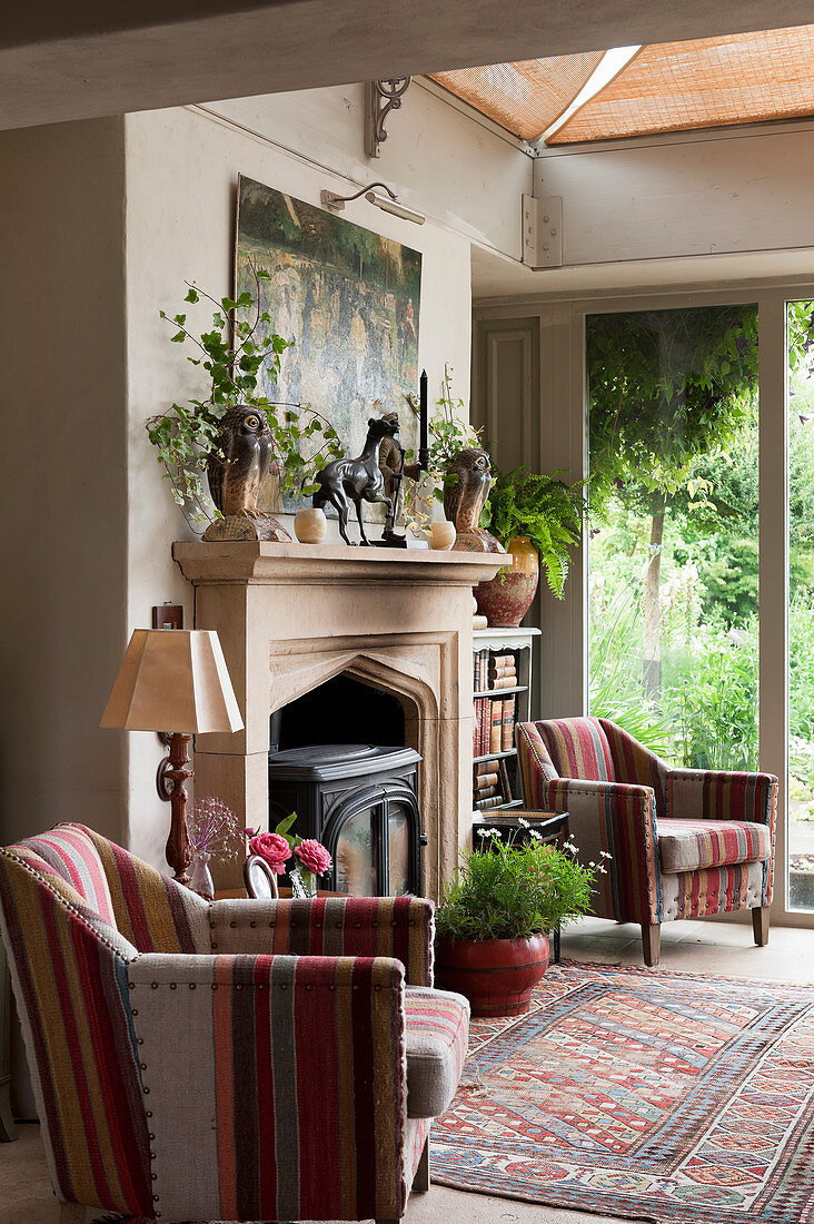 Two striped armchairs flanking fireplace in renovated English country house