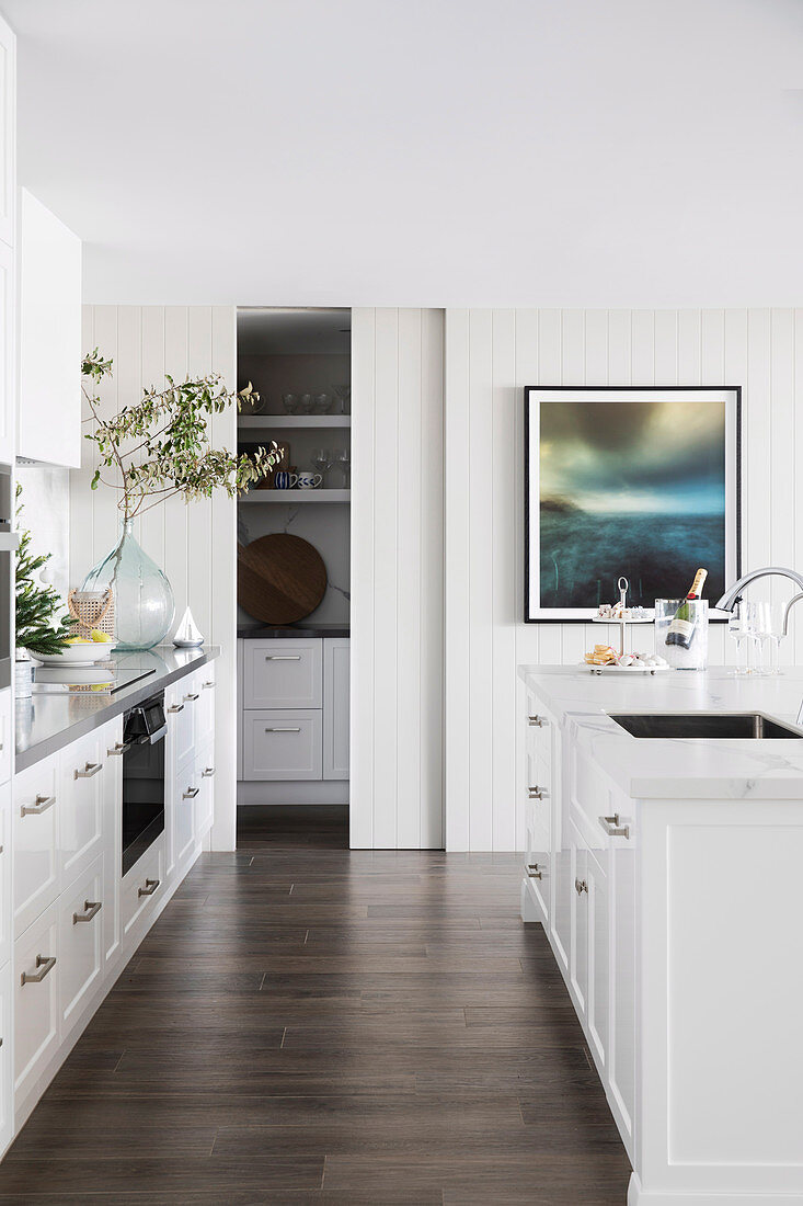 Blick in helle zeitgenössische Küche mit weißer Küchenzeile und Kücheninsel