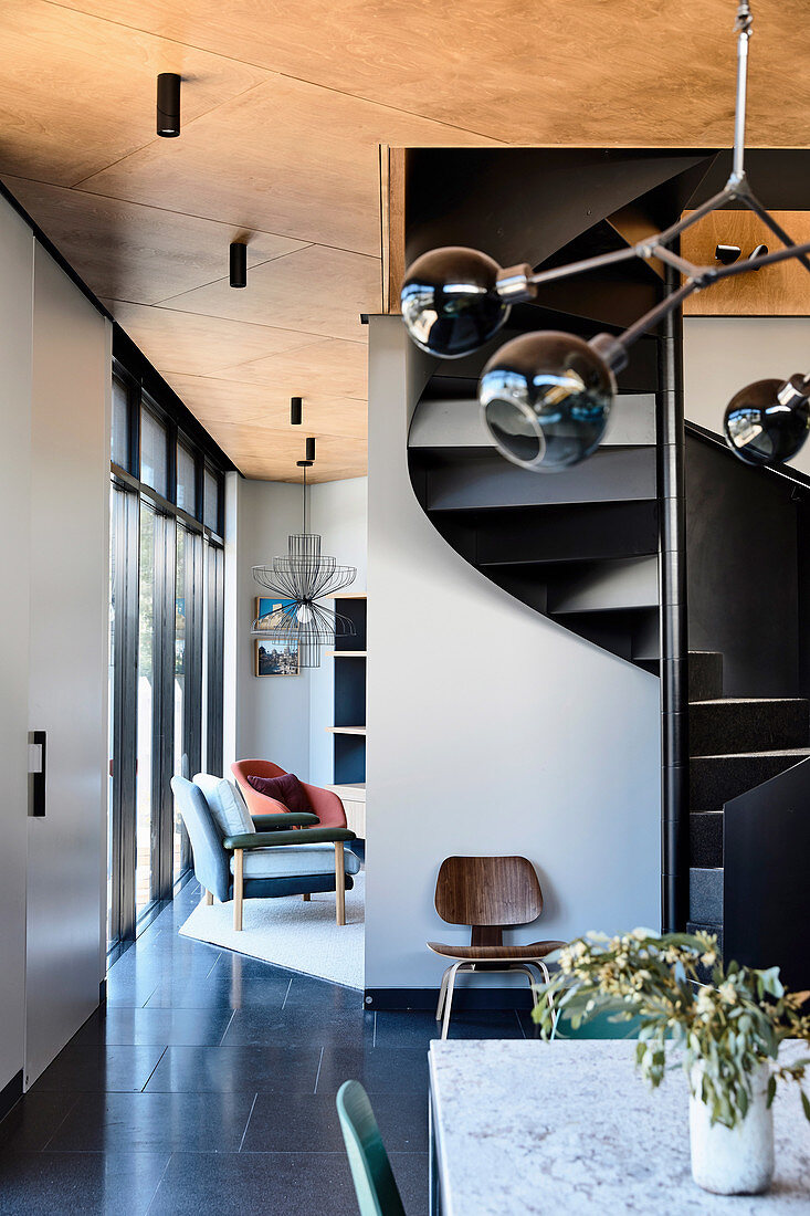 Spiral staircase in the open living room in shades of gray in the architect's house